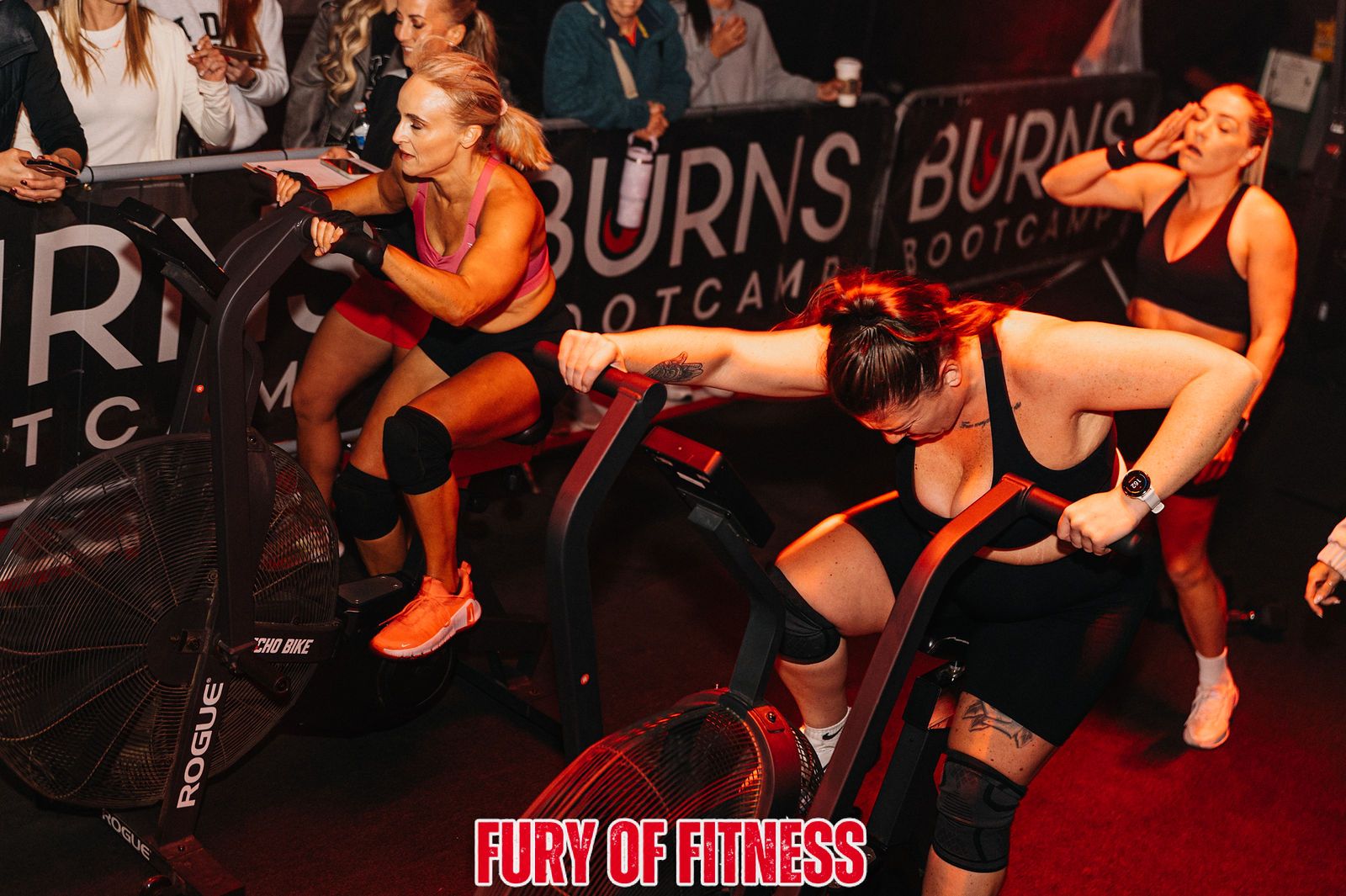 Athletes on the machines in front of a Burns Bootcamp banner at Fury of Fitness