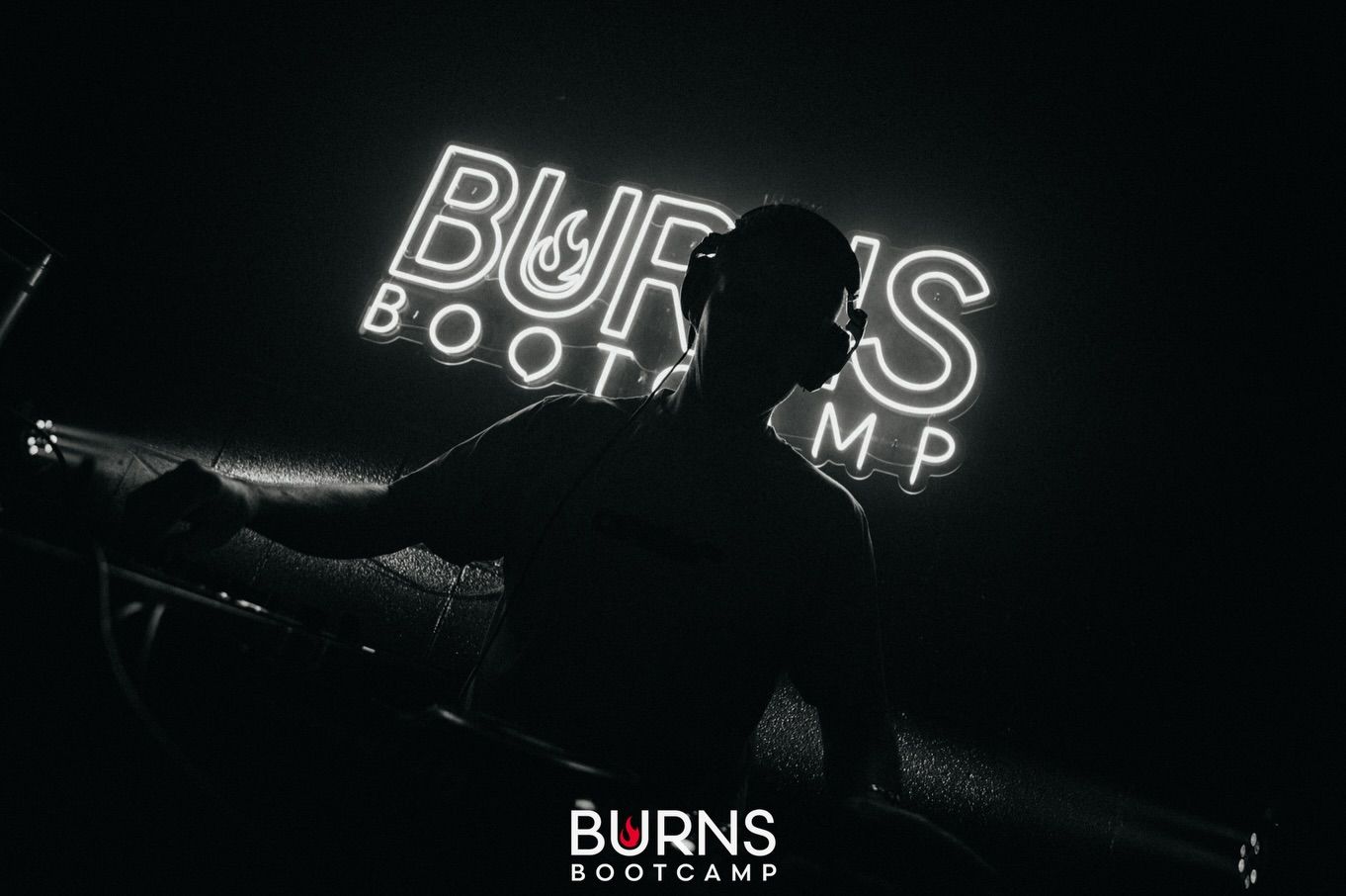 Neon Burns Bootcamp sign glowing in the dark studio